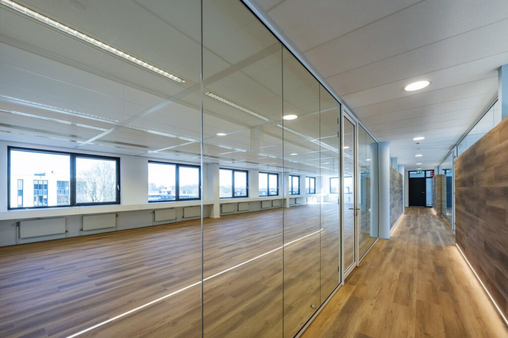 Modern office hallway with glass walls and wood-style flooring at Prof. W.H. Keesomlaan.